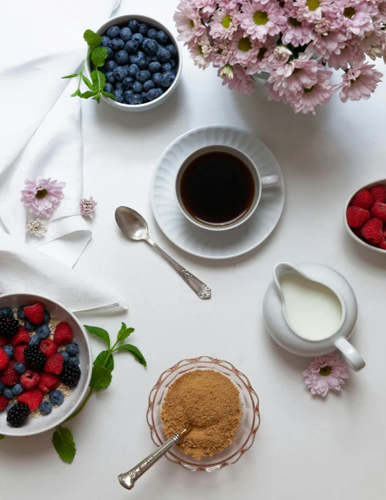 a white table topped with bowls of fruit and a cup of coffee, product image