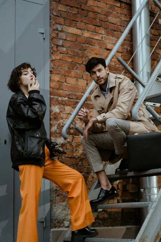 a man and a woman sitting on a set of stairs, by Adam Marczyński, trending on pexels, renaissance, trench coat, black and orange, brown pants, thumbnail