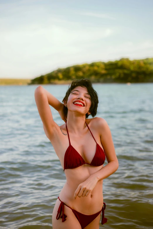 a woman in a bikini standing in the water, soft smile, in style of lam manh, giggling, at a beach
