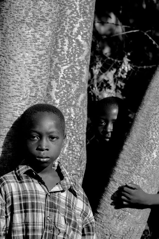 black and white pograph of two boys standing near tree