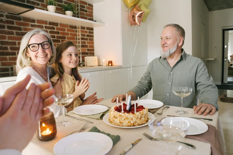 a group of people sitting around a table with a cake, food