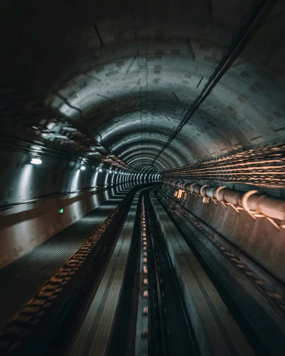 a train traveling through a tunnel at night, unsplash contest winner, futurism, sewer pipe entrance, conveyor belts, inside a marble, lgbtq