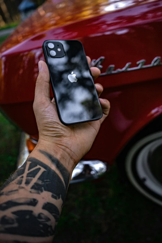 a close up of a person holding a cell phone, a tattoo, trending on pexels, apple car, black paint, 1.2, classic chrome