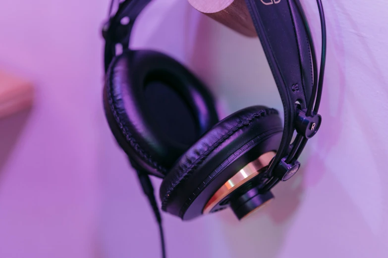 a pair of headphones hanging on a wall, trending on pexels, hyperrealism, gold and purple, avatar image, black and gold wires, studio 4°c