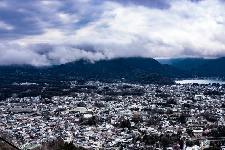 a mountain town under some cloudy skies with a river and mountain in the background