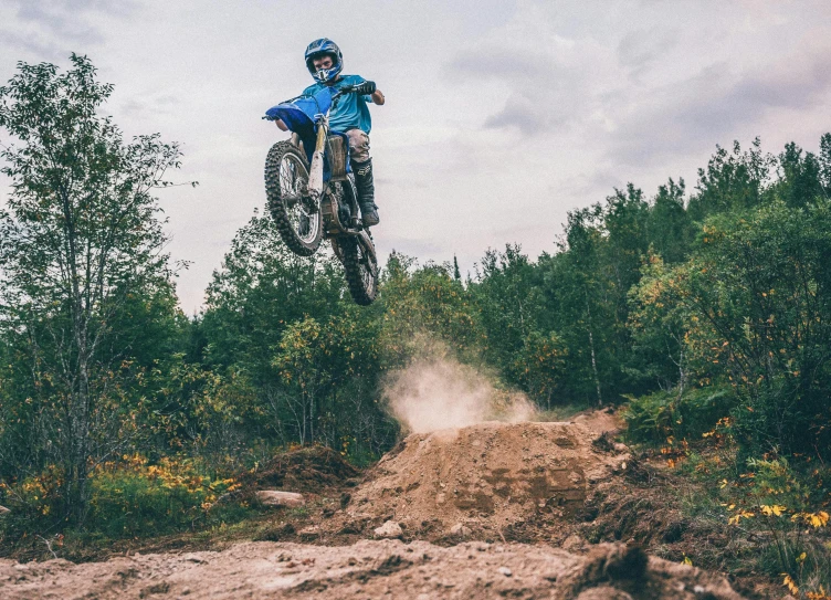 a guy on a dirt bike doing a jump off of a dirt road