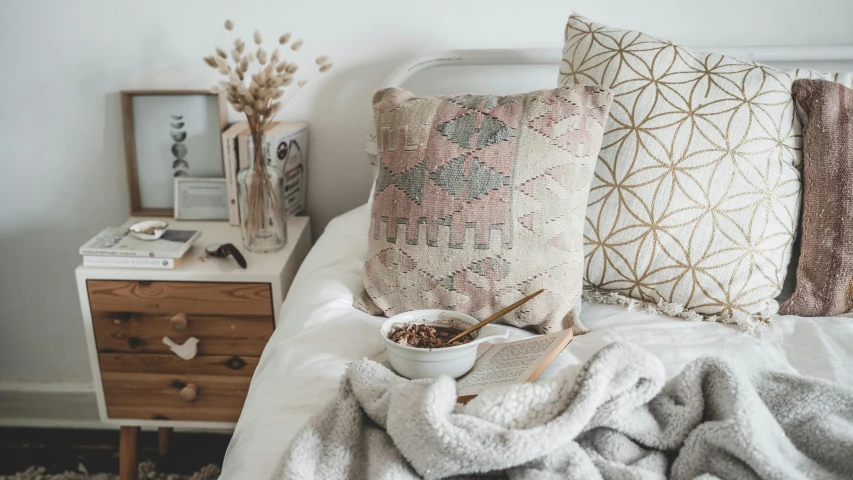 pillows and a bowl of cereal on a bed