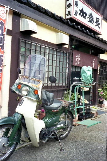 a green and white motorcycle parked in front of a building, shin hanga, old furnitures, in front of ramen shop, as photograph, square