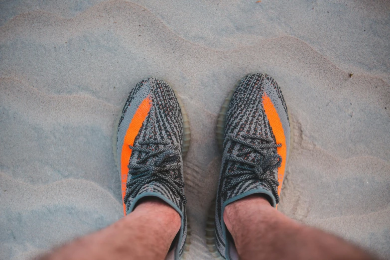 a person standing on top of a sandy beach, pexels contest winner, renaissance, yeezy collection, grey orange, closeup portrait shot, sitting on the ground