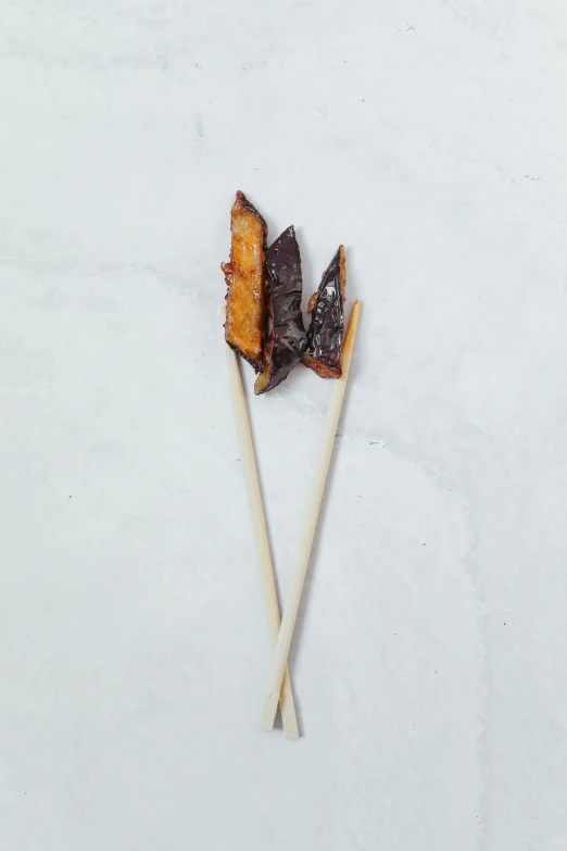 a couple of sticks sitting on top of a white surface, skewer, eggplant, v wing, made of glazed