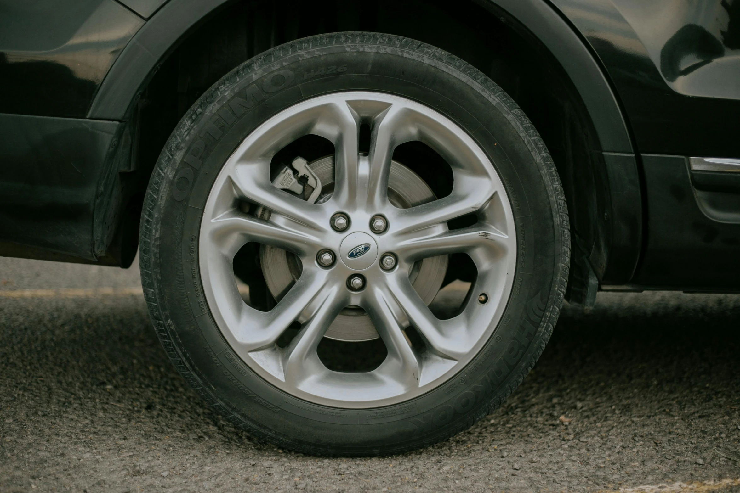 a close up of a tire on a car, by David Simpson, pexels contest winner, detailed alloy wheels, hyperrealistic shaded, outside in parking lot, high resolution photo