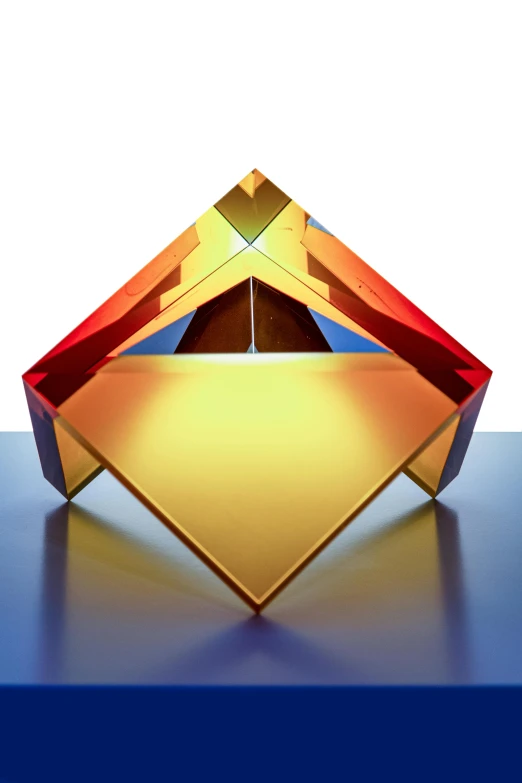 a close up of a colorful object on a table, inspired by Richard Anuszkiewicz, crystal cubism, shades of aerochrome gold, symmetric form exploration, lit from below, folded geometry