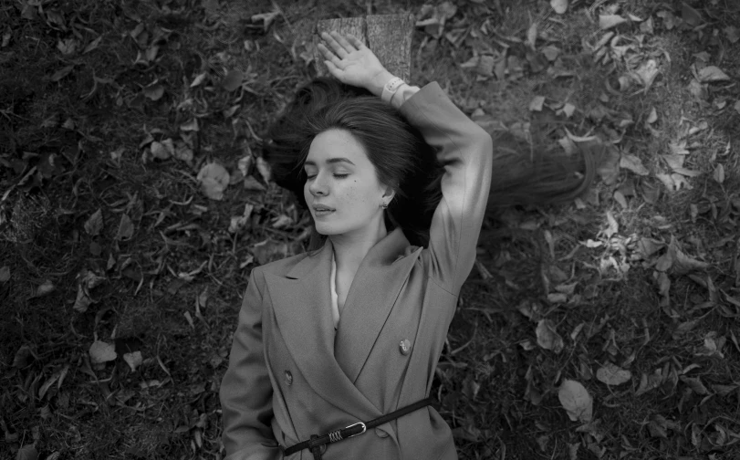 a black and white photo of a woman laying on the ground, by Maurycy Gottlieb, emily blunt, in style of joel meyerowitz, in autumn, with high cheekbones