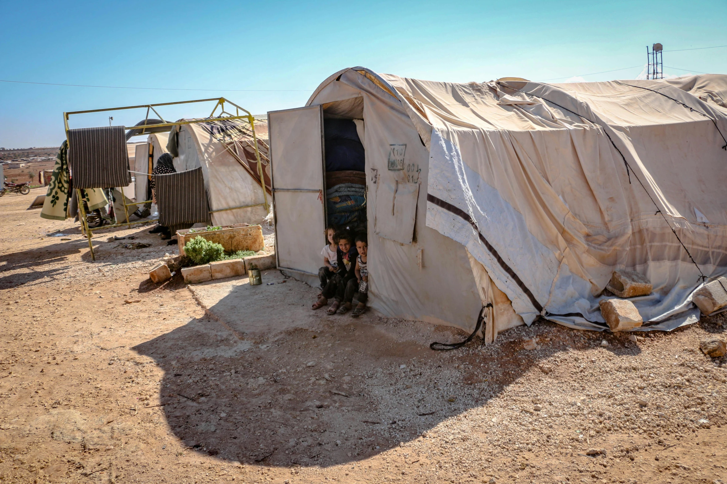 a couple of tents sitting on top of a dirt field, concrete housing, jordan, profile image, doors to various living quarters