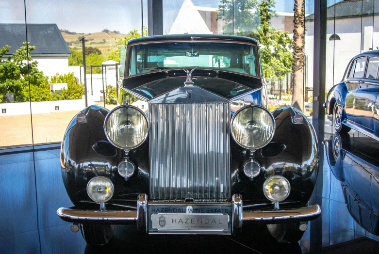 a classic car is on display in a museum, by Hubert van Ravesteyn, sparkling in the sunlight, wraith, front on, half and half