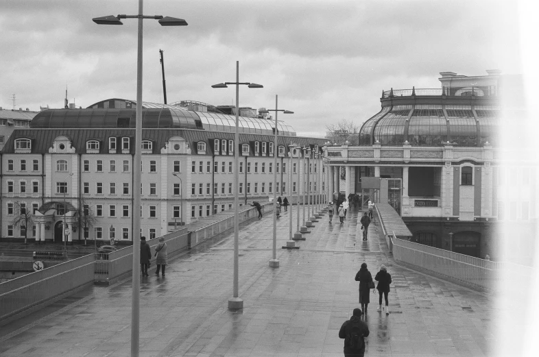 a black and white photo of people walking on a sidewalk, inspired by Thomas Struth, flickr, berlin secession, gloomy skies, crystal palace, post - soviet courtyard, olafur eliasson