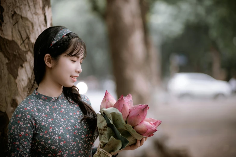 a woman holding a bunch of flowers next to a tree, inspired by Cui Bai, pexels contest winner, handsome girl, avatar image, young asian girl, casually dressed