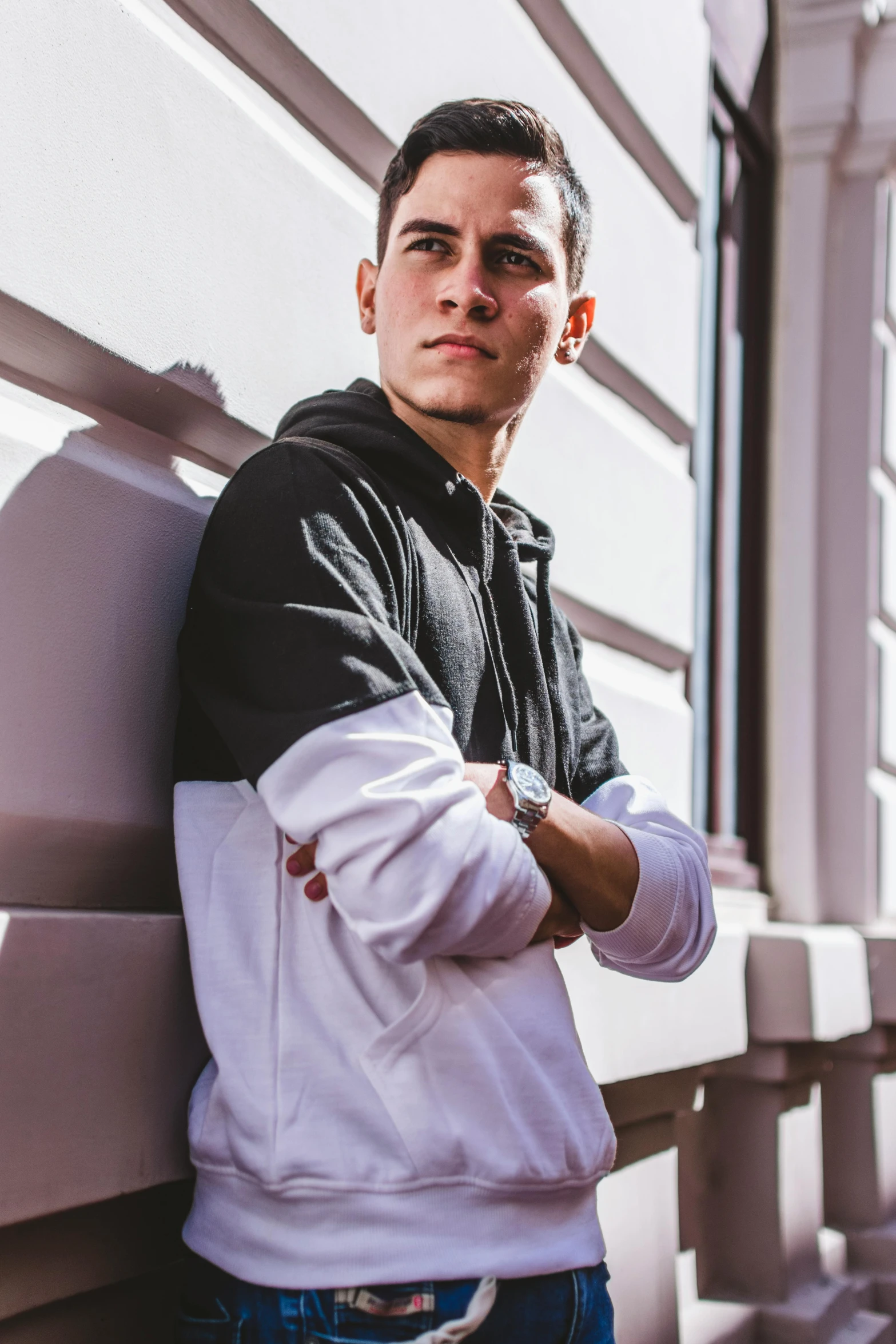 a man is leaning against the edge of a wall wearing a white and black hoodie