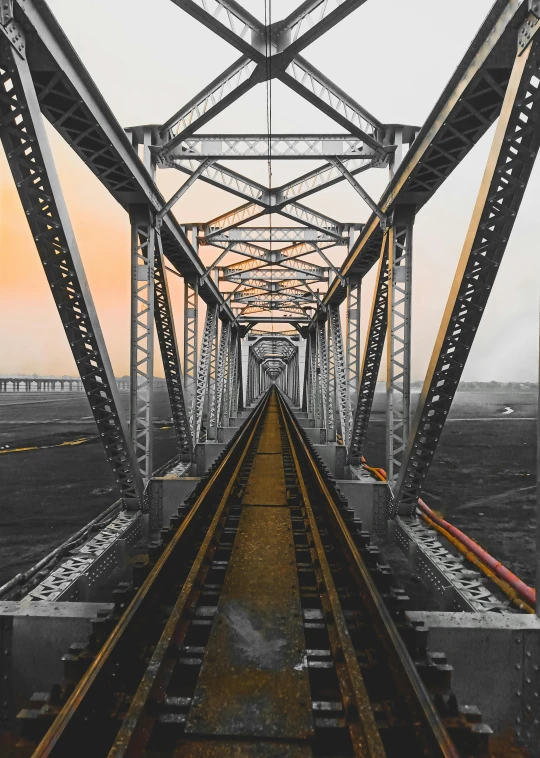 a black and white photo of a train track, a colorized photo, inspired by Christo, unsplash contest winner, howrah bridge, detailed color scan”, sunset view, ilustration