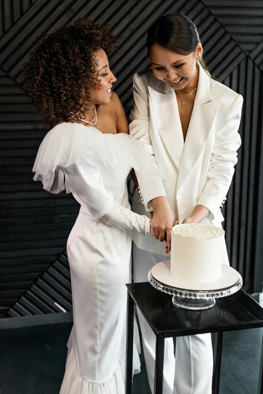 a man and woman cutting a cake together, by Julia Pishtar, wearing futuristic white suit, lesbians, elegant style, black