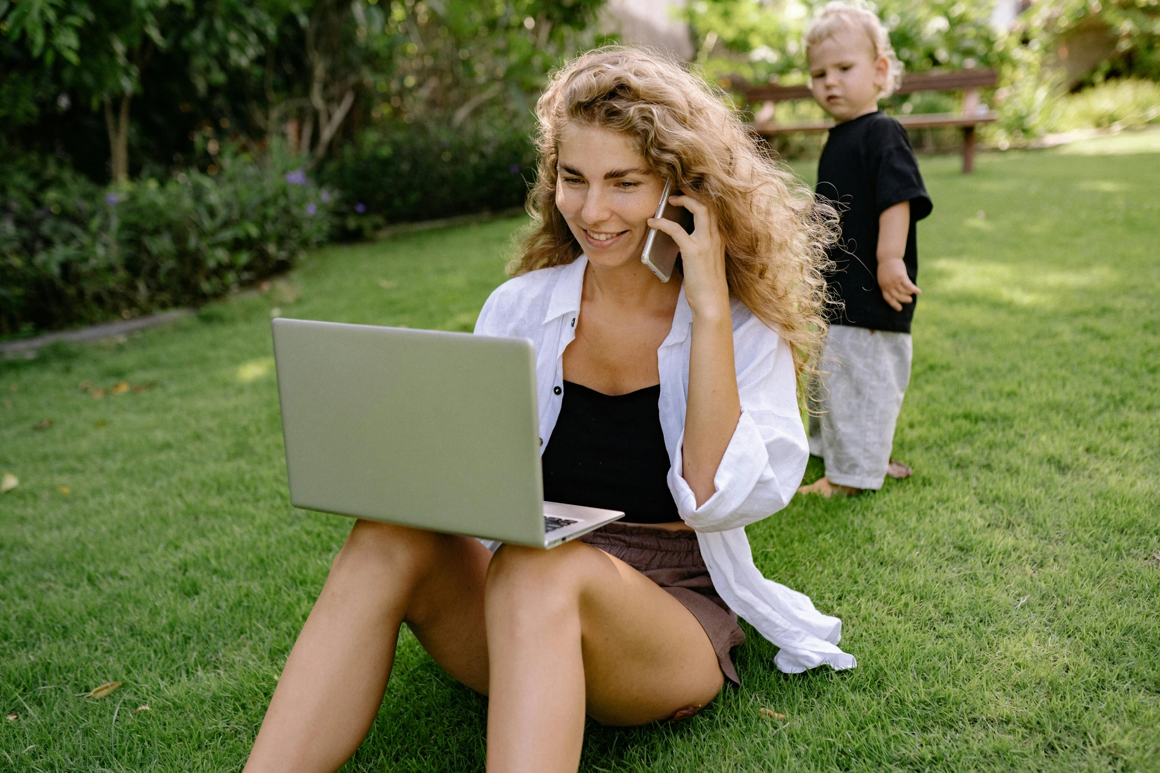 a woman sitting on the grass talking on a cell phone, a cartoon, pexels, with a laptop on his lap, families playing, a blond, working