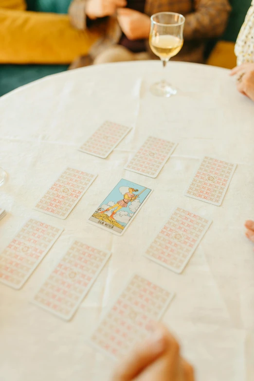 a group of people sitting around a table playing a game, inspired by Elsa Beskow, private press, wedding, pair of keycards on table, zoomed in shots, medium distance shot