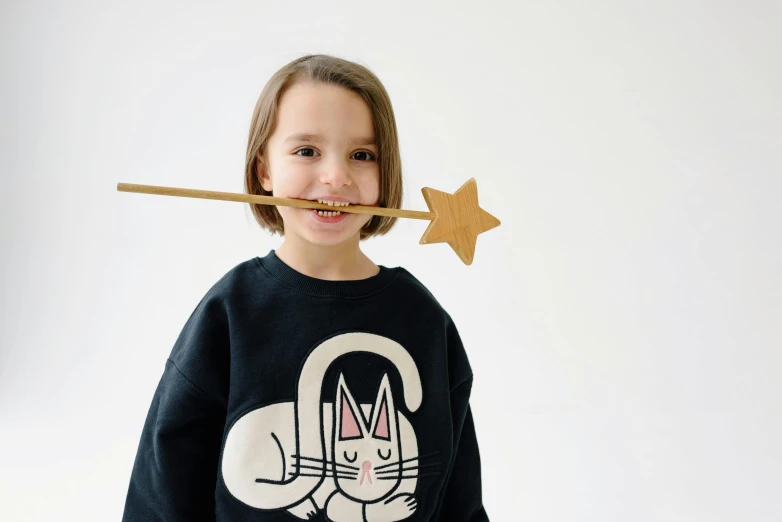 a little girl with a toothbrush in her mouth, a cartoon, inspired by Kanō Naizen, unsplash, magical realism, wearing sweatshirt, super math wizard cat, holding a wooden staff, product introduction photo