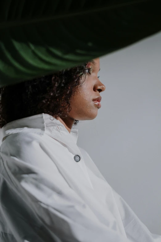 a woman sitting under a large green leaf, an album cover, inspired by Carrie Mae Weems, unsplash, wearing lab coat, close - up profile, dressed as a pastry chef, portrait image