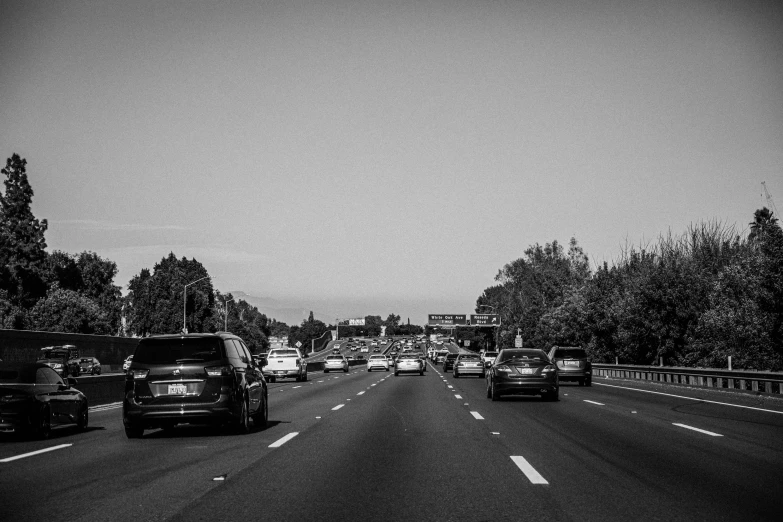cars and trucks travel down a freeway in black and white