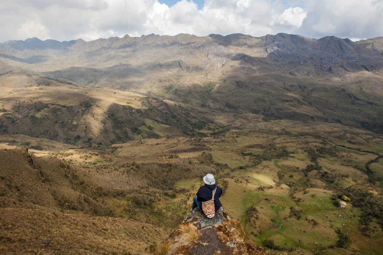 a person sitting on top of a hill looking at the mountains