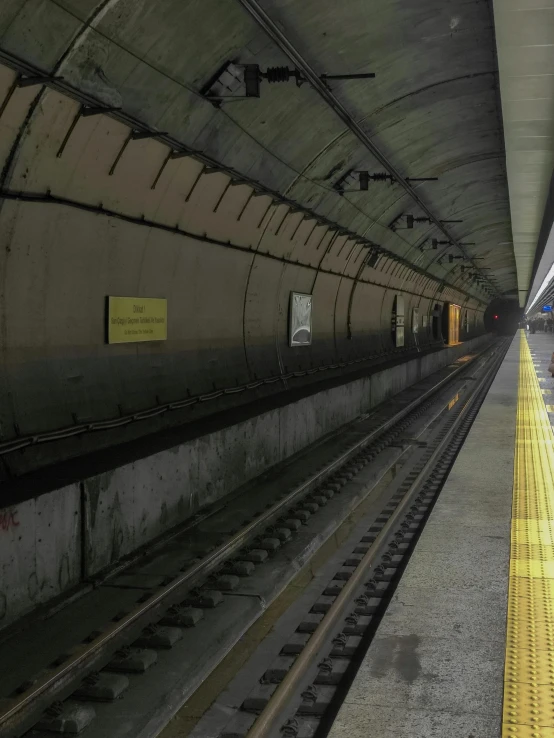 a train pulling into a train station next to a platform, a picture, by Alejandro Obregón, vancouver, dark train tunnel entrance, ground - level view, low quality photo