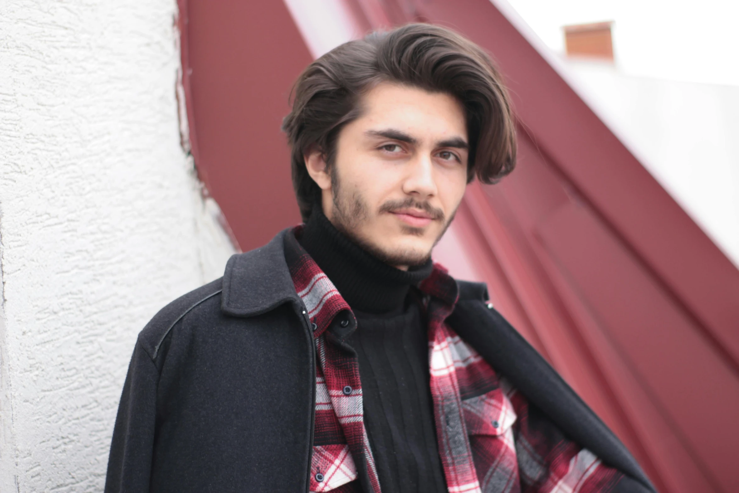 a young man standing by a wall next to a building