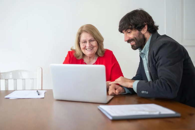 a man and a woman sitting at a table looking at a laptop, profile image, diane ramic, background image, professional shot