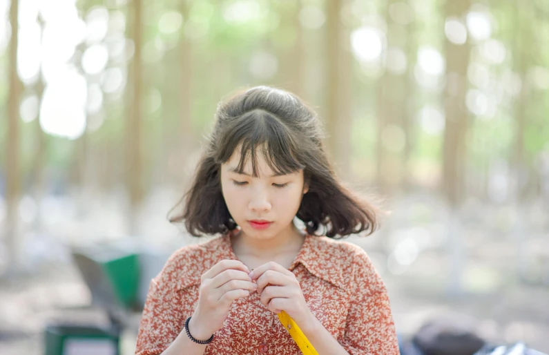 a woman standing in a forest holding a banana, pexels contest winner, portrait of a japanese teen, holding pencil, thoughtful, crayon