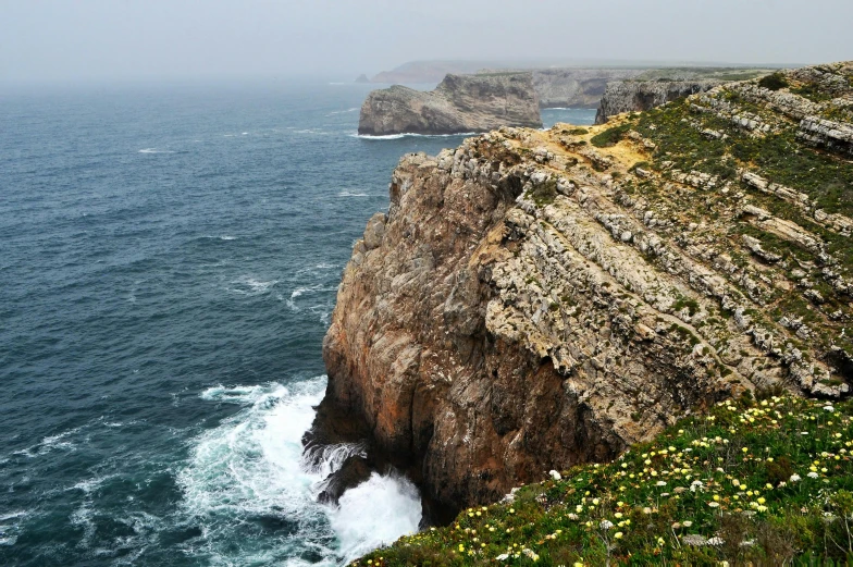 a man standing on top of a cliff next to the ocean, pexels contest winner, portugal, grazing, national geograph, texture