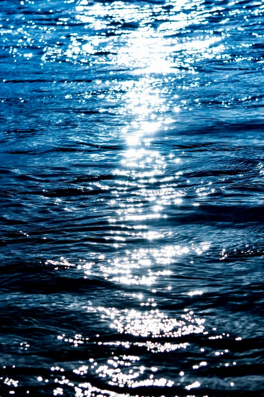 the sun shines brightly on a body of water, dark blue water, sparkling water, swirly lunar ripples, brightly-lit