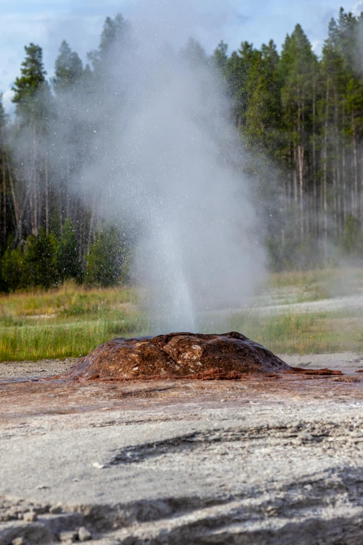 a geyser is spewing water over a dirt mound