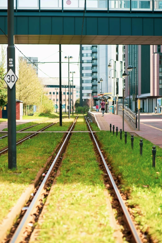 a train track going under a bridge in a city, coventry city centre, in an eco city, telephone wires, canary wharf