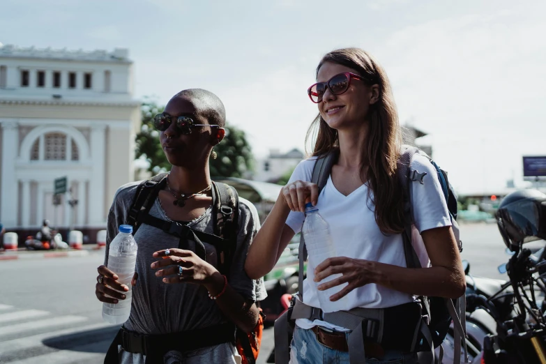 a couple of women standing next to each other on a street, pexels contest winner, hydration, a backpack, avatar image, wearing shades