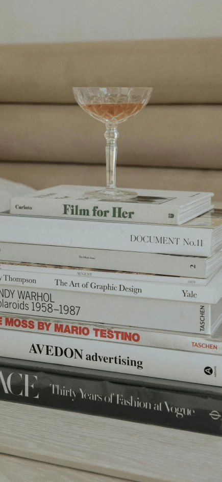 a stack of books sitting on top of a table, by Celia Fiennes, video art, off - white collection, sofia coppola, in style of norman foster, high quality photo