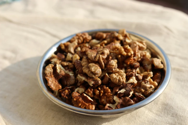 nuts in a metal bowl on top of a cloth