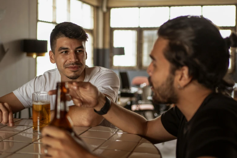 two men sitting at a bar drinking beer, pexels contest winner, avatar image, mexican standoff, aussie baristas, young greek man