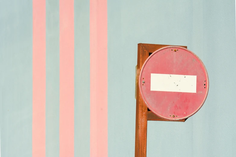 a red and white sign sitting on top of a wooden pole, an album cover, inspired by Wes Anderson, unsplash, postminimalism, pastel blues and pinks, striped, traffic light, pastel pink concrete