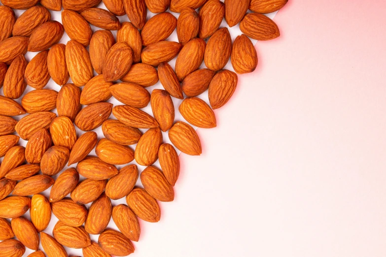 a pile of almonds on a pink background, by Gavin Hamilton, pexels, hyperrealism, 🦩🪐🐞👩🏻🦳, background image, fruit, recipe