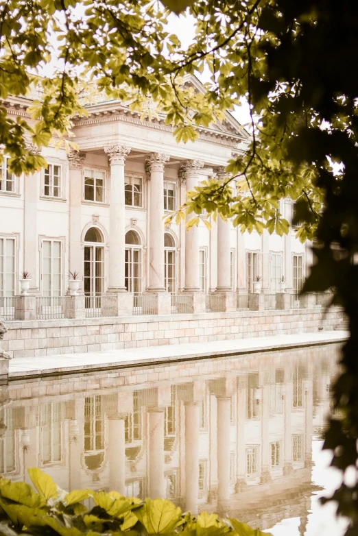 a large building sitting next to a body of water, a picture, inspired by Mihály Munkácsy, trending on unsplash, neoclassicism, pale colors, berlin park, lots de details, soft glow