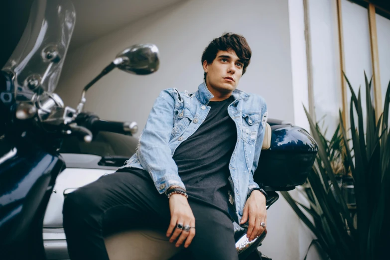 young man sitting on motorcycle looking away from camera