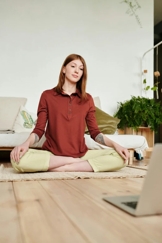 a woman sitting on the floor in front of a laptop, trending on pexels, renaissance, red shirt brown pants, lotus pose, a redheaded young woman, no - text no - logo
