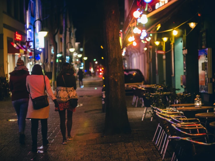 a couple of people walking down a street at night, pexels contest winner, two girls, memphis, hannover, colorful scene