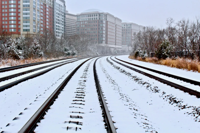 a train track covered in snow next to tall buildings, by Washington Allston, washington dc, fan favorite, skidding, istock