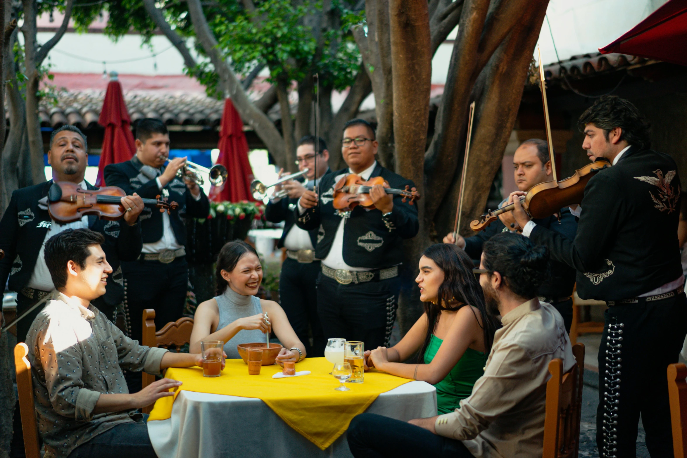 a group of people sitting around a yellow table, el dorado, musicians playing instruments, netflix, at a dinner table